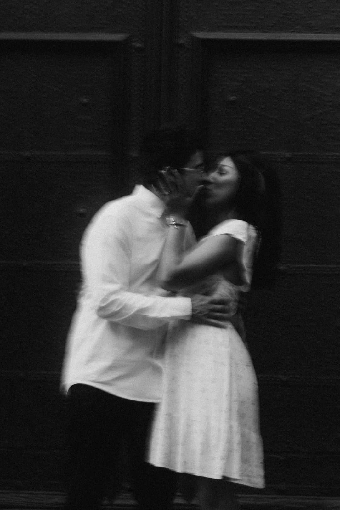 David y Banellye besándose frente a una puerta oscura, foto en blanco y negro